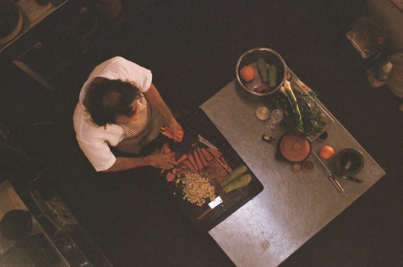 George, seen from above, chopping carrots and vegetables on a wooden board