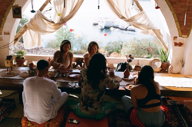 Guests sharing a meal at the low table, the Nile through the open window